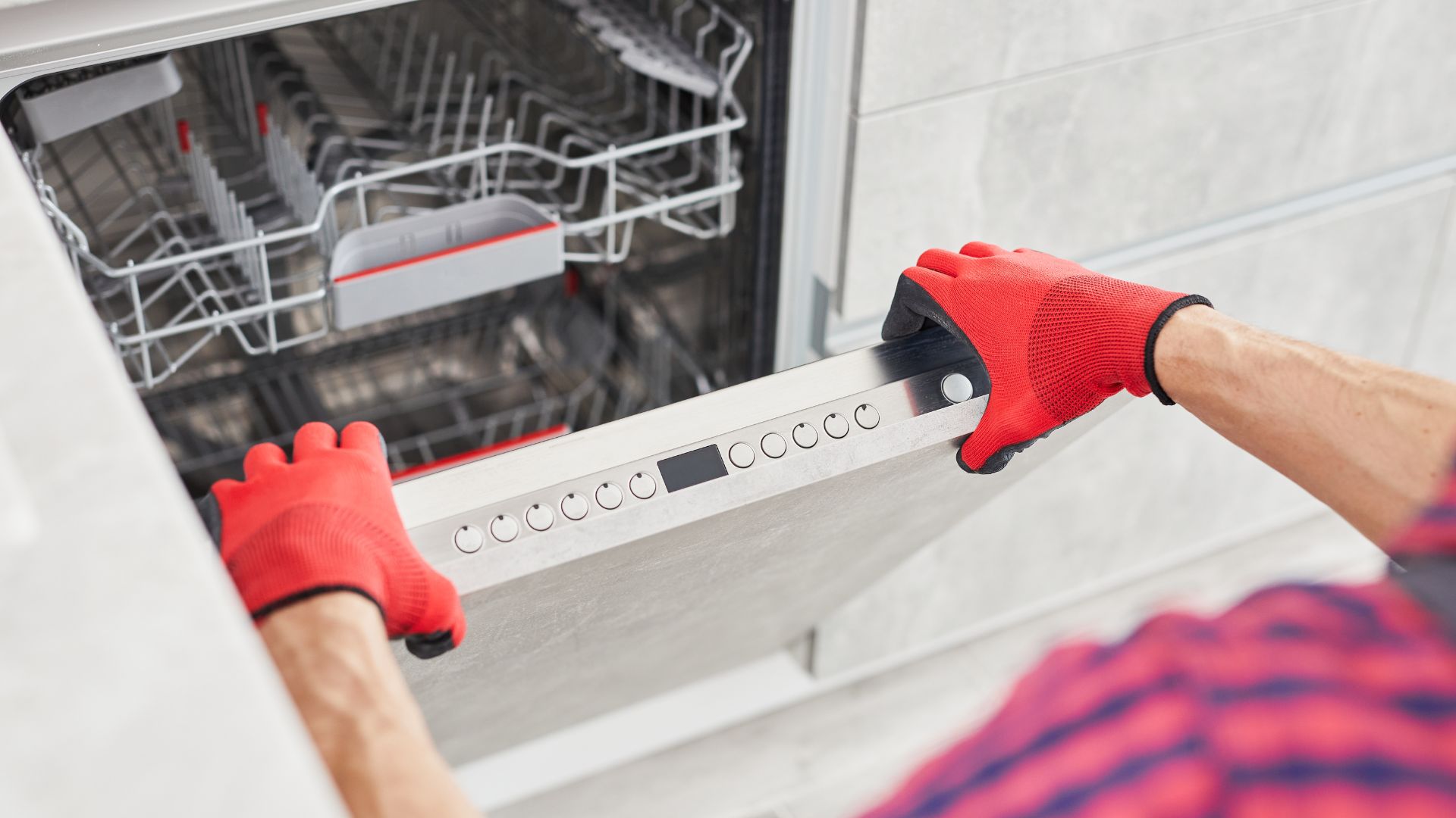 A man in red gloves is opening a dishwasher
